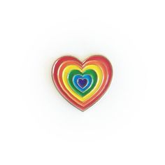 a rainbow heart shaped pin on a white background