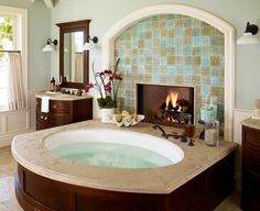 a large jacuzzi tub sitting in the middle of a bathroom next to a fireplace