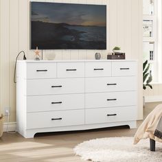 a white dresser in a bedroom with a large tv on top of it's cabinet