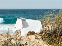 there is a white structure on the sand by the ocean with waves in the background