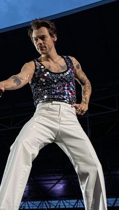 a man in white pants is performing on stage with his hands out to the side