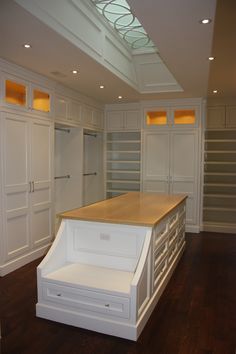 an empty kitchen with white cabinets and wooden counter tops, in the middle of a dark wood floor