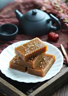 three pieces of fushi on a plate with chopsticks and teapot in the background