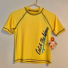 a yellow shirt hanging on a hanger next to a white wall with an advertisement