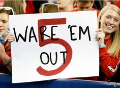 two women holding up a sign that says 5 are em out in front of them