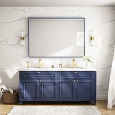 a bathroom with marble walls, blue vanity and gold faucet sinks in it