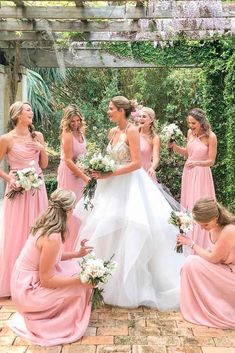 a group of women in pink dresses standing around each other and one woman holding a bouquet