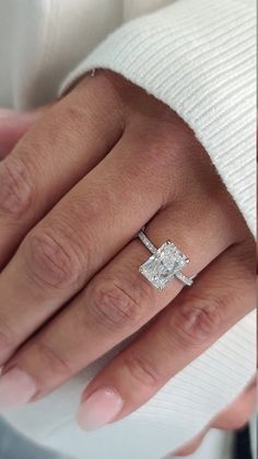 a woman's hand with a diamond ring on top of her finger and an engagement band