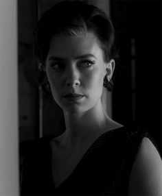 black and white photograph of a woman in a dark room looking at the camera with an intense look on her face