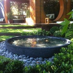 an outdoor fountain surrounded by grass and rocks