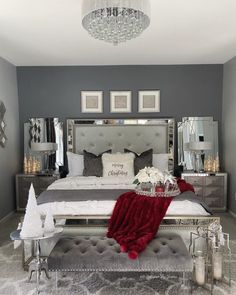 a bedroom decorated for christmas with silver furniture and white decorations on the bed, chandelier