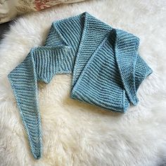 a blue knitted sweater laying on top of a white rug