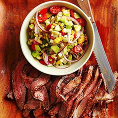 a wooden cutting board topped with meat and vegetables next to a knife on top of it