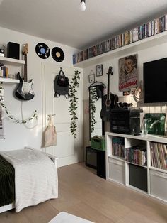 a bedroom with white walls and lots of books on the shelves, guitar headphones hanging from the ceiling