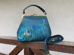 A small retro handbag. Teal green leather crossbody wallet purse. Hand painted Peacock Feather art luxury top handle bag and shoulder bag in vintage style. It is a beautiful Frame bag with a kiss lock. It is a stylish and noble ladies' frame bag with a clip closure. Made of good dense skin, will keep the shape, of what will be put inside, will not crumble, and will not bend. It's a small shoulder and cross-body bag made of genuine dollar leather. A rigid structure. Kiss lock frame closure. Insid Leather Sling Bag Men, Hand Painted Bags Handbags, Painted Handbags, Crossbody Wallet Purse, Peacock Feather Art, Hand Painted Bags, Kiss Lock Purse, Painted Peacock, Hand Painted Purses