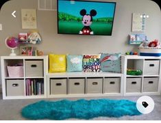 a child's bedroom with mickey mouse on the tv and toys in bins