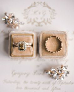 an engagement ring sits in a box next to two wedding rings on top of it