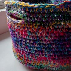 a multicolored basket sitting on top of a window sill