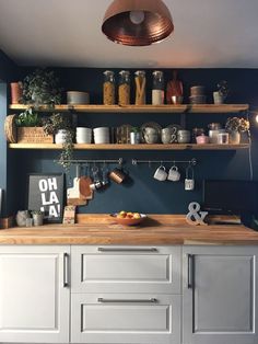 a kitchen with wooden counters and shelves filled with pots, pans and utensils