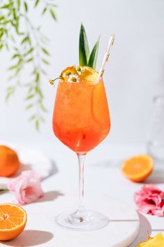 an orange cocktail garnished with flowers and leaves