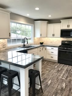 a kitchen with white cabinets, black appliances and counter tops is pictured in this image