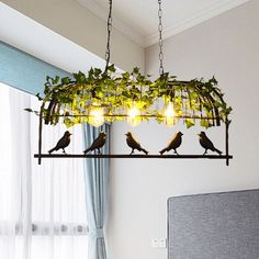 three birds sitting on a branch hanging from a chandelier over a bed in a bedroom