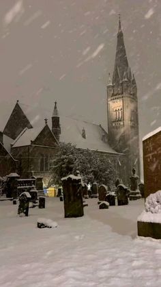 a snow covered cemetery with a clock tower in the background