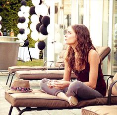 a woman sitting on top of a lounge chair next to a table filled with black and white balloons