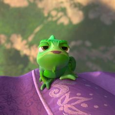 a green frog sitting on top of a purple umbrella