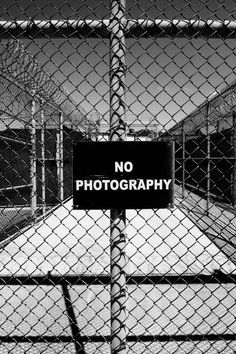 a black and white photo of a fence with a no photography sign on it