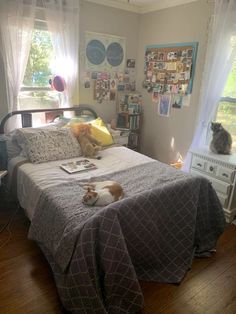 two cats sitting on the edge of a bed in a room with wood flooring