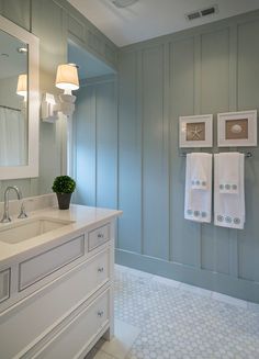 a bathroom with gray walls and white fixtures on the vanity, along with towels hanging on the wall