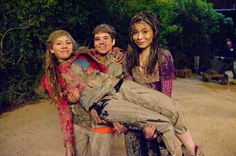 three young people posing for a photo in the dirt with one holding a woman on her back