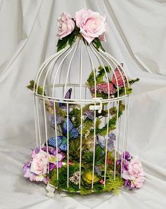 a white birdcage filled with flowers and butterflies