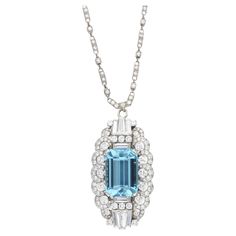 Raymond Yard necklace featuring a stunning emerald-cut aquamarine, weighing approximately 21 carats. This center stone is accented by round, baguette, and tapered baguette-shaped diamonds, weighing a total of approximately 10 carats. These stones are set on platinum, and are approximately G-H color and VS clarity. Pendant is marked "Yard." Total weight: 37.12 grams. Chain length: 18 inches. Pendant length: 2 inches. Width: 1.25 inches. The pendant can be converted into a brooch. Luxury Aquamarine Necklace With Diamond Accents, Exquisite Silver Diamond-cut Necklace, Blue Brilliant Cut Pendant Jewelry, Luxury Aquamarine Pendant Jewelry, Exquisite Diamond-cut Pendant Necklaces, Art Deco Pendant Necklace, Diamond Flower Pendant, Gemstone Brooch, Vintage Pendant Necklace