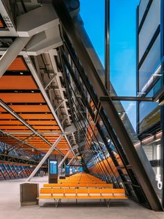 an orange bench in the middle of a building with glass walls and metal railings