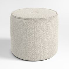 an upholstered round ottoman sits in front of a white background and looks like it could be used as a footstool