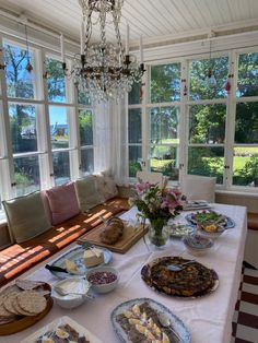 a table topped with lots of food next to a window filled with windows covered in curtains