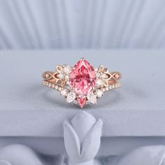 a pink diamond ring sitting on top of a white table next to a stuffed animal