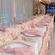 the table is set with pink napkins and place settings for an elegant dinner party