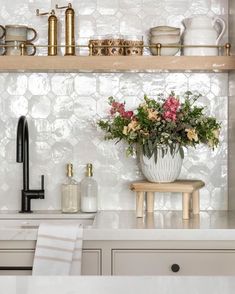 a vase with flowers sitting on top of a kitchen counter