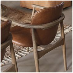 two brown leather chairs sitting next to each other on top of a carpeted floor