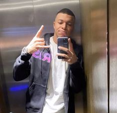 a man taking a selfie with his cell phone in front of an elevator door