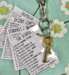 four keys are attached to a keychain on a flowered tablecloth with the names of different parents and students