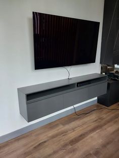 a flat screen tv mounted to the side of a wall in a room with wood flooring