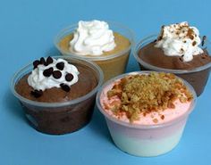 four different desserts in plastic cups on a blue surface