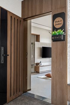 an open door leading to a living room with a television on the wall and plants in pots