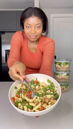 a woman sitting at a table with a bowl of pasta salad in front of her