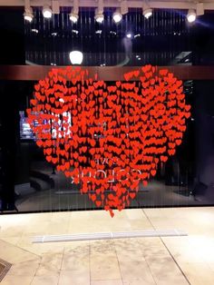 a large heart made out of red hearts in front of a glass window with the words love you written on it