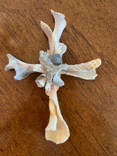 a cross made out of seashells on a wooden table